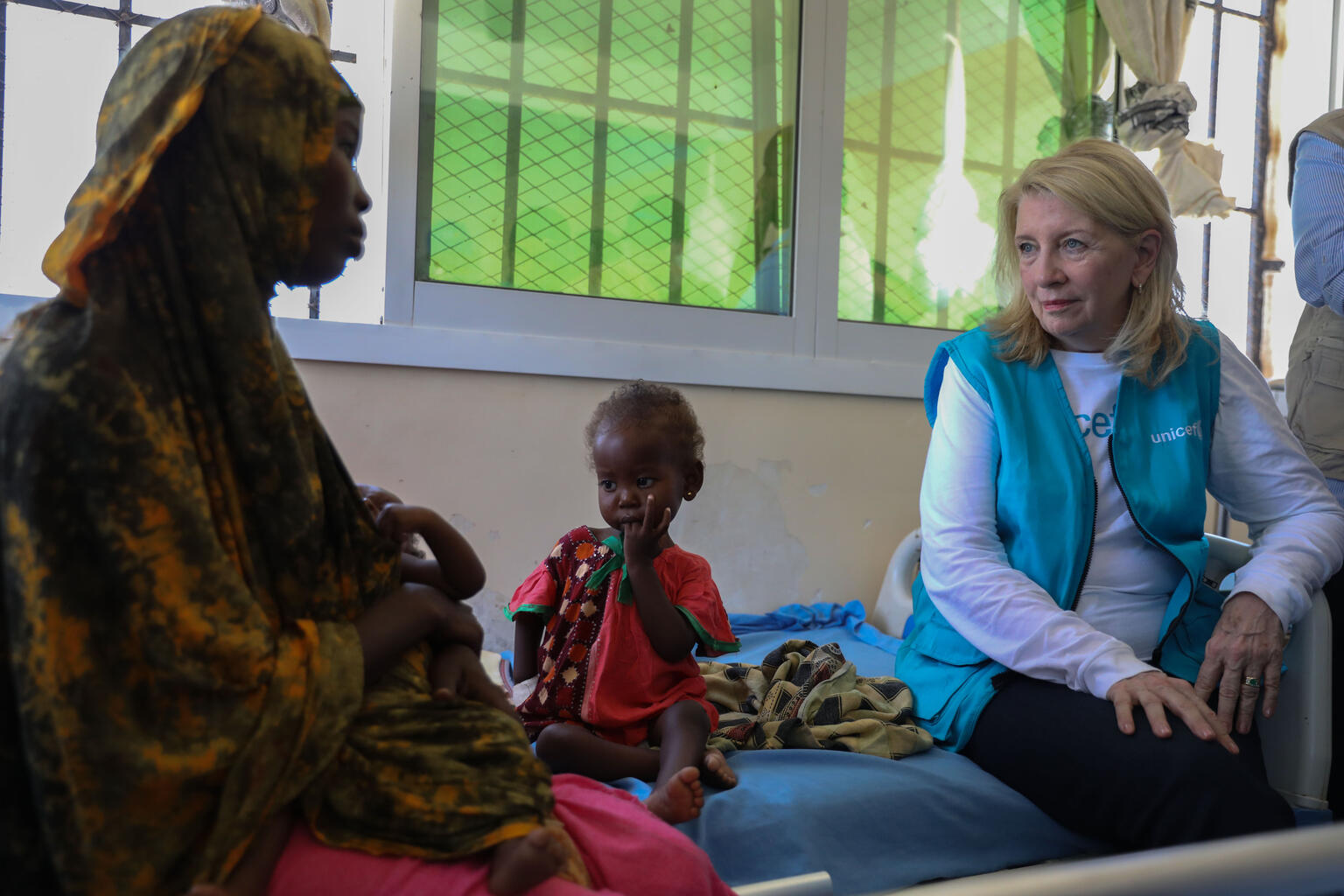 南部ドローの病院で、重度の急性栄養不良と合併症の治療を受けている子どもの母親から話を聞くラッセル事務局長(右)(ソマリア、2026年3月25日撮影)