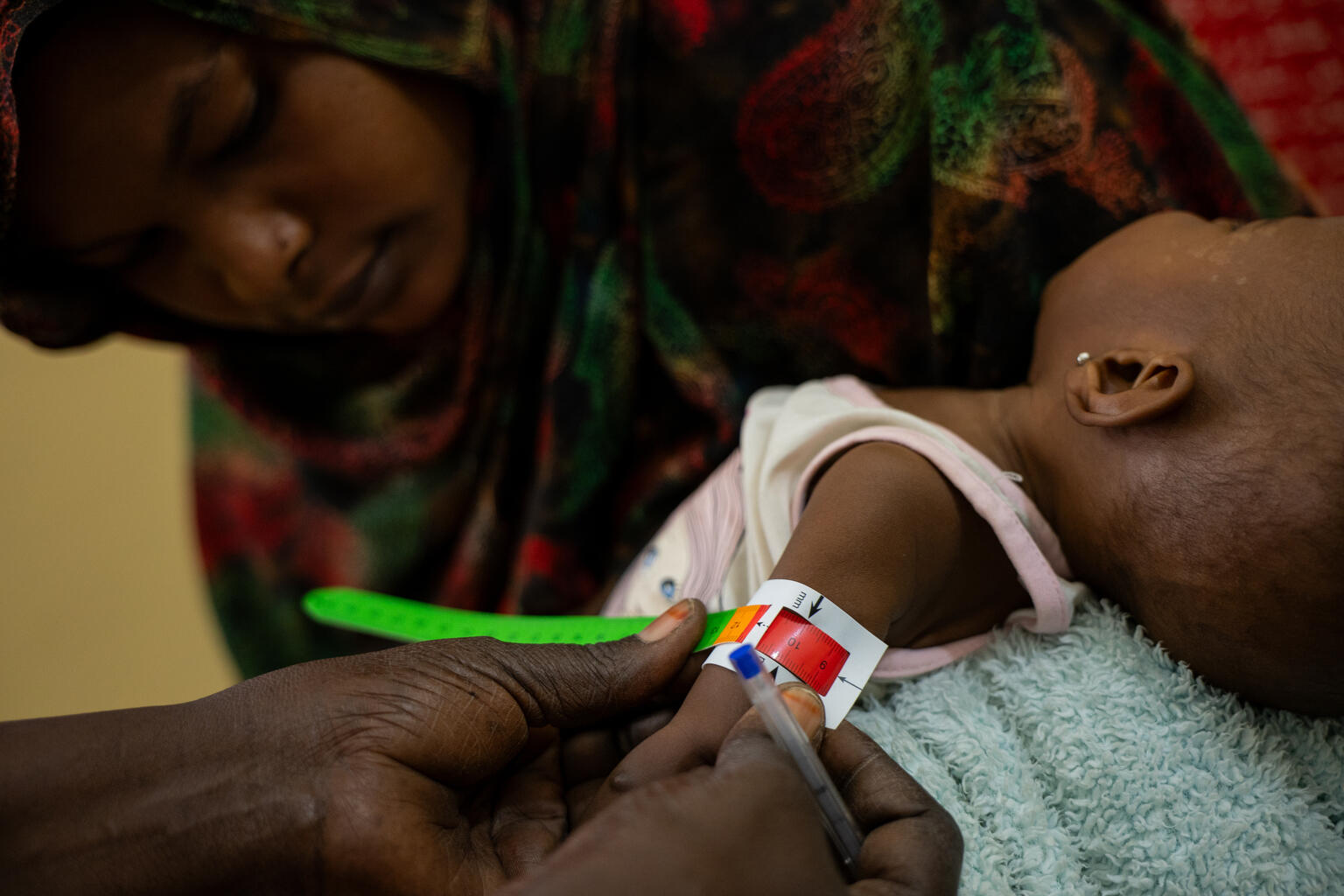 ジャジーラ州の保健センターで、上腕計測メジャーを使った検査により栄養不良を意味する「赤」が示された子ども（スーダン、2026年3月16日撮影）