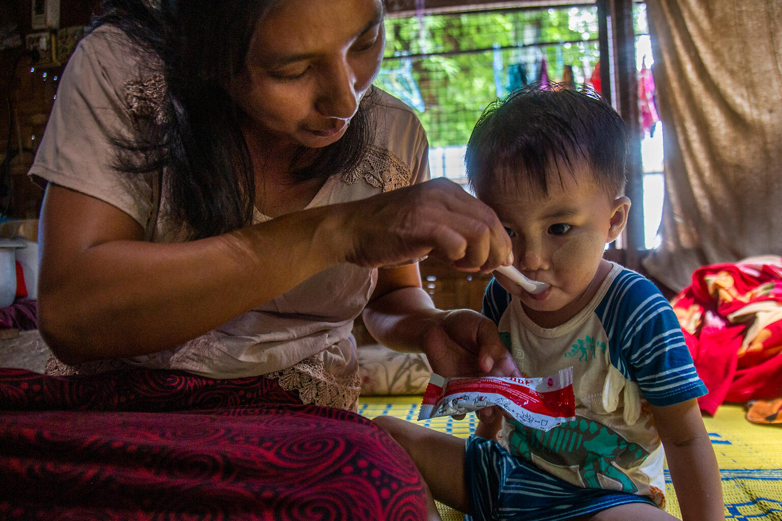 地震の被害が大きかったマンダレーで、すぐに食べられる栄養治療食（RUTF）を食べさせてもらう2歳のシン・ミン・エイちゃん。地震後、栄養不良に陥ったが、ユニセフの支援で少しずつ回復している（ミャンマー、2025年9月22日撮影）