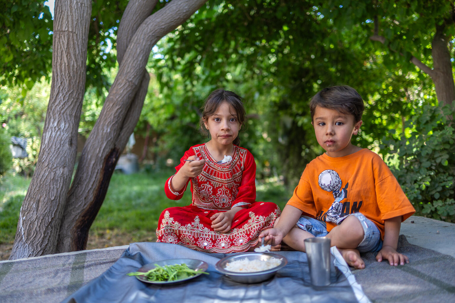 ヘラート州カディスタン村の自宅で、昼食をとるザイナブさん(左)と弟のローエーンちゃん。アフガニスタンでは、多くの子どもたちが十分に栄養のある食事をとることが難しい状況にある(アフガニスタン、2026年5月21日撮影)