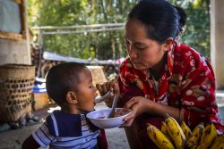自宅の裏庭で育てた食材を使って栄養のある食事を作り、娘に食べさせるドー・ブー・シェインさん(ミャンマー、2022年2月4日撮影)