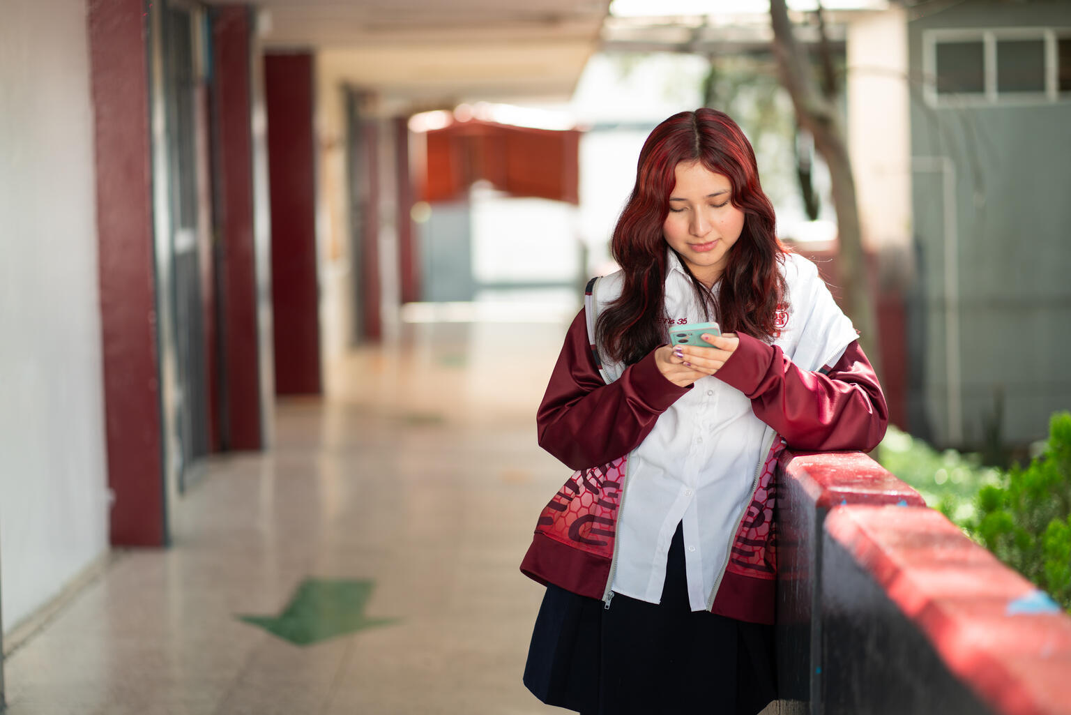学校の廊下で、スマートフォンの画面を見つめる17歳のジェラルディンさん(メキシコ、2025年9月24日撮影)
