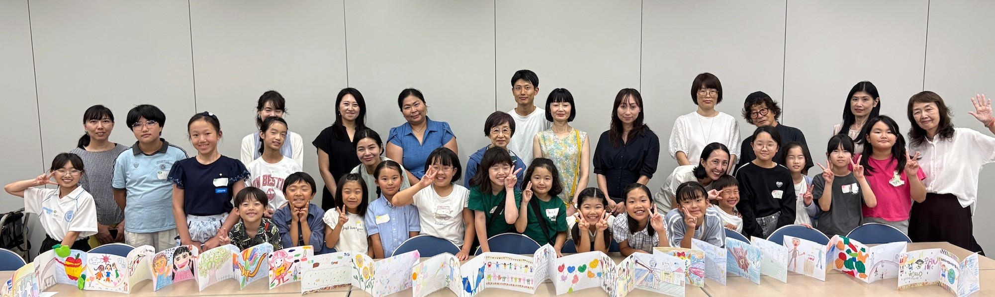 それぞれが描いた絵を一つにつなげた「ちきゅうパスポート」を前に記念撮影。右端は『ちきゅうパスポート』の発起人の一人、絵本作家の石川えり子さん