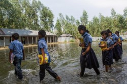 洪水の水が引かない中、学校に登校する生徒たち。