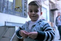 冬用キットを受け取る列に並ぶおじさんを待つ男の子。