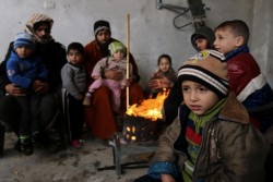 ガザ地区の破壊された自宅で、家族と一緒に焚火の周りに集まって暖を取る子どもたち。