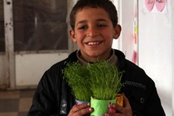 安全に学び、遊ぶことのできる「子どもにやさしい空間」で育てる植物を手に、笑顔を見せるアハメドくん（10歳）。