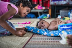 小学校の避難所で7カ月の赤ちゃんと遊ぶ9歳の女の子。サイクロンで多くの子どもたちが避難生活を強いられている。