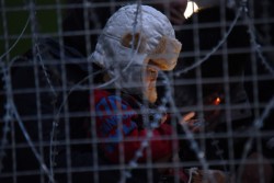 難民や移民のためのトランジットセンターの近くにあるフェンスの前に立つ幼い子ども。(ギリシャ)