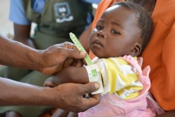 上腕部を測り、栄養状態の検査を受ける女の子。