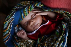 毛布に包まれて眠る生後3週間の赤ちゃん。（中央アフリカ共和国）