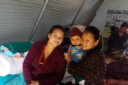 ユニセフが支援する避難所でアユシュくんを抱くグラン保健担当官と、母親のアヌジャさん。