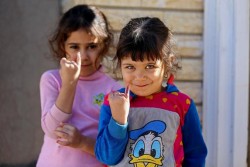 ポリオの予防接種を受けた小指に付けられた紫色の“しるし”を見せる子どもたち。（イラク）