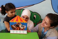 ユニセフ教育専門官とともに、ユニセフのECDキットに含まれている指人形を使って遊ぶ、シリアの女の子(5歳)。