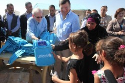 ヨルダンのザータリ難民キャンプに新設された学校でユニセフの支援物資を子どもたちに手渡すユニセフ事務局長。
