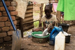 教会の敷地で避難生活を送り、屋外で食器を洗う女の子。（南スーダン・ワウ州　2016年7月28日撮影）