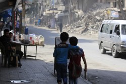 破壊されたアレッポの街を肩を組んで歩く子どもたち(本文と直接の関係はありません）（2016年8月撮影）。