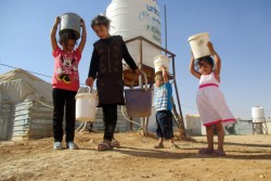 シリアとの国境に近い、ヨルダンのザータリ難民キャンプにて水を汲む子どもたち。
