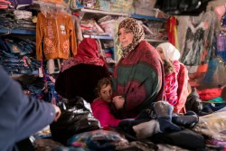 一時給付された現金を使い、ザータリ難民キャンプ内の店で子どもの服を買う母親。（2016年12月1日）
