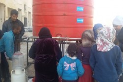 On 7 December 2016, People queue to collect water from a tank installed by UNICEF in the district of Hanano in east Aleppo, which is now housing displaced families, and those returning, in partially damaged buildings. UNICEF is trucking safe drinking water for more than  1,250 families in the area. UNICEF immediately responded to the needs of families and installed 10 water tanks in Hanano, each with a capacity of 5,000 liters. Some 31,5000 people are reported to have been displaced from and within eastern Aleppo City since 24 November. Temperatures are dropping quickly and heavy rainfall has made conditions even worse over the past few days. UNICEF is providing blankets and winter clothing, as well as access to safe water, essential medical care, including vaccinations and psychosocial support for children who have lived through such horrors. In Jibreen, to the east of Aleppo City, children and their families displaced by recent fighting in eastern Aleppo take shelter in a large warehouse in an area under Government control. Some 8,000 people are sheltering there. In Hanano, in east Aleppo City was the first district to be retaken by Government forces on 27 November. People are now moving back to the area as the frontline of fighting has moved further away. This includes families returning to their homes, as well as displaced families from other areas of east Aleppo.