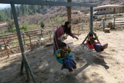Pema Eden with five-year-old twins Nima and Dawa. The play station outside the center was constructed by parents of the children enrolled there.