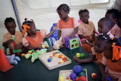 Children play with Early Childhood Development (ECD) kits inside a UNICEF tent at St Benedict school, in a IDP camp located in a former golf course. Since March 2010, over 1.495 kits have been distributed by UNICEF throughout  the country to support Haitian Ministry of Education and NGO partners in maintaining childhood development programs.