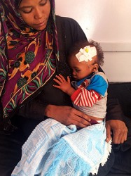 お母さんの腕に抱かれるアブドゥくん。栄養不良および脱水症状と診断されたが、通院にかかる費用が賄えず、治療の中断を余儀なくされていた。イエメン・サヌア：ユニセフが支援するアル・サビン病院にて）