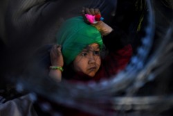 ギリシャの難民・移民一時収容施設近くにあるフェンスの横に立つ子ども (2016年2月撮影)