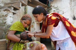 20歳の母親バビタさんが、生後15日の新生児に授乳している。ユニセフのカウンセラー（写真右）は、各家庭をまわり、正しい母乳育児の方法について伝えている。（インド）