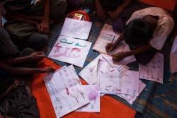 On 29 September 2017, Rohingya children draw at the children friendly space at the Balukhali makeshift refugee camp in Cox’s Bazar district in Bangladesh.  A quarter of a million Rohingya children have fled Myanmar since the latest outbreak of violence began a month ago.Many more continue to cross the border into Bangladesh every day. Many are alone, have nothing and some have a hard time speaking about what they've seen. Instead, they draw pictures to help cope with the horrific scenes they've experienced and witnessed. UNICEF announced 30 September 2017 that it is planning to establish more than 1,300 new learning centres for Rohingya children who have fled Myanmar to neighbouring Bangladesh. UNICEF is currently running 182 learning centres in Rohingya camps and makeshift settlements in Cox’s Bazar, and has enrolled 15,000 children. It plans to increase the number of learning centres to 1,500, to reach 200,000 children over the next year. The learning centres provide early education to children aged 4 to 6, as well as non-formal basic education to children from ages 6 to 14. In each learning centre there are three shifts, with each shift comprising of 35 children. Children learn English, Math, Burmese, Science, Arts and Anthems in the learning centres. Children also receive psychosocial counselling, and are taught hygiene and life skills.  The children are given books, pens, colouring pencils, school bags and other educational materials. Over a quarter of a million Rohingya children have fled Myanmar into Cox’s Bazar since August 25.