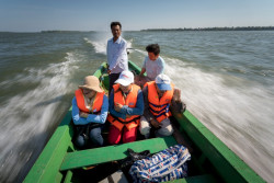 遠く離れたコミュニティにワクチンを届けるため、メコン川をボートに乗って進むバナックさんと保健チーム。