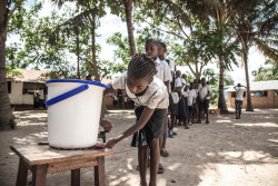 On 22 May 2018, children wash their hands to help contain the Ebola outbreak before entering a classroom in the north-western city of Mbandaka, in the Democratic Republic of the Congo. UNICEF has installed hand-washing points in 50 targeted schools in affected areas in the port city. Following the announcement by the Government of the Democratic Republic of the Congo (DRC) on 8 May 2018 of a new Ebola outbreak in Equateur Province, UNICEF has mobilised its teams to help contain the spread of the disease. The outbreak was declared in the Bikoro Health Zone, located more than 100 kilometers south of the provincial capital of Mbandaka. A UNICEF team with two doctors, a specialist in water, sanitation and hygiene as well as a specialist in community communication left today from Mbandaka to assess the extent of the epidemic and begin implementing the response, alongside the Government and the World Health Organization (WHO). This is the ninth Ebola outbreak in the country since 1976. UNICEF supports the Government in its coordination of the response both from the country’s capital Kinshasa as well as in the affected area. UNICEF has been active in the Equateur Province for many years. Based on its experience in previous Ebola epidemics, UNICEF is focusing its response on communication activities in the communities to protect people from the disease and on water supply, hygiene and sanitation to prevent the spread of the disease. UNICEF has already sent a total of 45 kg of chlorine, five sprays, 50kg of soap and 28,000 water purification tablets to the area, as well as 600 posters and 6,000 leaflets to educate affected communities.