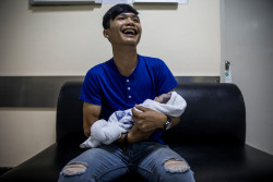 タイの病院で、生まれたばかりの赤ちゃんを抱き涙する父親。(2018年3月撮影)