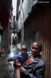 ケニア・ナイロビで、建物の合間の路地に立つ子どもを抱えた母親。(2016年9月撮影) 