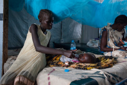 南スーダンのジュバにある病院で、ペットボトルの水を妹に飲ませる姉。