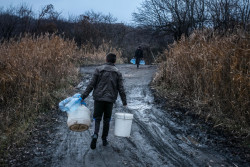 Ivan Morhun, 23, who is one of nine children, carries empty containers to fetch water in the city of Toretsk, Donetsk Oblast, Ukraine, Monday 20 November 2017. Ivan's family lived through a short period when their city was on the contact line, which divides government and non-government controlled areas and where fighting is most intense, and was frequently shelled. The family have frequently experienced prolonged periods when they have no water due to water pipes leading to their town being damaged in fighting. Even when water is running normally – for short periods in the morning and evening – the family sometimes run short and have to fetch drinking water from a local spring. In the months when water was completely shut off, the queues at the spring were hours long. As of December 2017, the situation in eastern Ukraine remains volatile, and violence continues despite the latest ceasefire agreements committed on 19 July 2017. The lives of children and their families, especially those living along the contact line continue to be at risk. Civilian infrastructure continues to be hit, putting an added strain on the ability to provide sustained access to basic social services. The disruption of critical infrastructure in settlements along the contact line is becoming the daily ‘normal’ for millions of people. Life-saving water and electricity installations were subject to continuous interruption in 2017, affecting more than three million people on both sides of the contact line. Multiple pumping stations, including the large Donetsk Filter Station (DFS) remain at the centre of hostilities. In February, water stoppages due to damaged power lines, and shelled filter stations placed the heating systems of around 1.8 million people directly at risk, with the town of Avdiivka particularly affected. While hostilities continue near critical infrastructure, damage to supply systems and – as a knock-on effect – the collapse of inter-dependent heating systems may