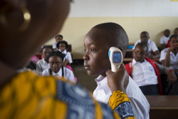 On 2 September 2019, (left) Jacqueline Maga Znigire, Deputy Director of The Volcano School of Goma, capital city of North Kivu province, Democratic Republic of the Congo, instructs students attending the first day of school on how to protect themselves from Ebola. Here she uses a digital thermometer to check the temperature of a student. A high temperature is an early sign that one may have Ebola. Schools have reopened for an estimated two million children living in communities affected by the Ebola outbreak in the eastern Democratic Republic of the Congo (DRC). There are 6,509 primary and secondary schools in Ebola-affected areas of Ituri, North Kivu and South Kivu Provinces – 3,800 of them are in high-risk areas. As of 3 September, most have reopened for the new school term. Among the students returning to class are hundreds of school-age Ebola survivors and children orphaned by Ebola. The Ebola outbreak in eastern DRC has now resulted in more than 3,000 confirmed cases, and over 2,000 deaths. More children, proportionately, are being affected than in any previous Ebola outbreak. At the start of the outbreak in August 2018, many parents, fearful of their children contracting the virus, kept them home from school. Teachers were ill-equipped to educate their students and the community on Ebola, or to aid those affected. Over the past year, UNICEF has worked closely with the Ministry of Education and other partners to map and deliver targeted assistance to schools, teachers, parents and students in affected areas. This includes equipping schools with thermometers, hygiene supplies and handwashing stations and training school administrators and teachers on everything from prevention measures to basic case management if a student or teacher begins to show symptoms. Teaching materials were produced, including an instruction guide with child-friendly illustrations that helps teachers teach children about how the disease spreads, how to prevent it and good hygiene p