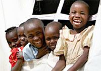 ユニセフの支援で設置された仮設の学校で、友達と笑顔を見せる８歳のイボンヌちゃん（写真右端）。