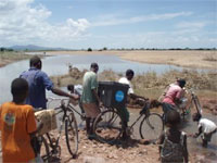 ときには、支援物資を自転車に積んで運ぶこともあります。道は洪水に流されてしまいました。
