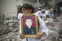 写真：倒壊した学校で亡くなった息子の遺影を抱える母親
