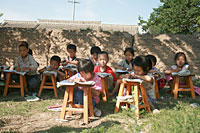 写真：木の下で臨時の授業が再開。