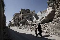 破壊された町を歩く親子。シリア、マアラタル・ヌマーンにて。