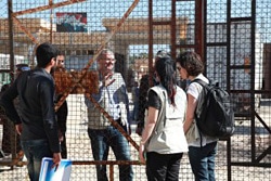 国境に備え付けられたフェンス越しに話をするシリアとトルコ両国のユニセフ職員。