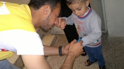 子どもに予防接種を受けた“しるし”をつけるボランティアスタッフ