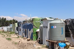日本政府支援による貯水タンク、隣にあるのはトイレ、ビニールシートに覆われているのがシリア難民の住居