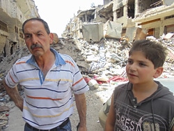 ホムス旧市街で破壊された家を目にした親子