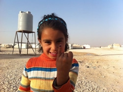 ポリオの予防接種を受けた子どもの指に着けられる紫色の印を見せる、ヨルダンに避難しているシリア難民の子ども。