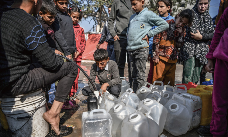 安全な飲み水を確保するため、順番を待って水の供給を受ける11歳の男の子（ガザ地区）