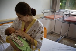 病院で赤ちゃんをあやす母親。（ルーマニア）