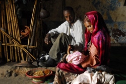 赤ちゃんに母乳をあげる母親と見守る父親。（エチオピア）